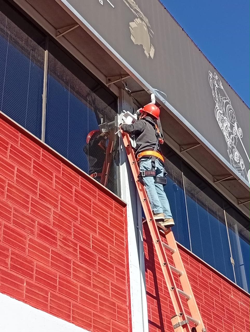 Profissional da Aletel realizando uma instalação externa em altura